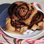 plate of chocolate peppermint cinnamon rolls stacked with candy canes surrounding the plate