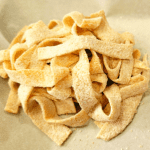 close up of uncooked fresh floured Kamut pasta noodles piled in a nest