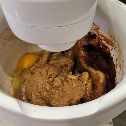 white mixing bowl that has fresh milled rye flour an egg and cocoa powder getting ready to mix