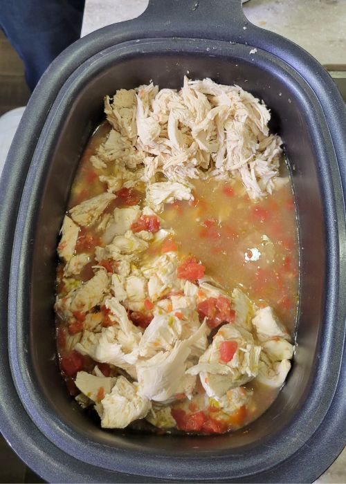 slow cooker crockpot full of cooked chicken breast and salsa