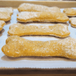 close up of a tray of baked Pumpkin Einkorn Dog Treat Bones. they look puffy and hollow in the middle