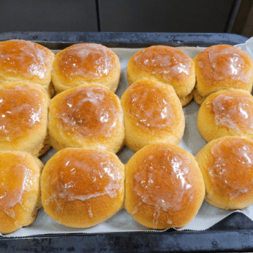 Tray of fresh baked sweet yeast whole wheat dinner rolls brushed with melted butter making them shiny