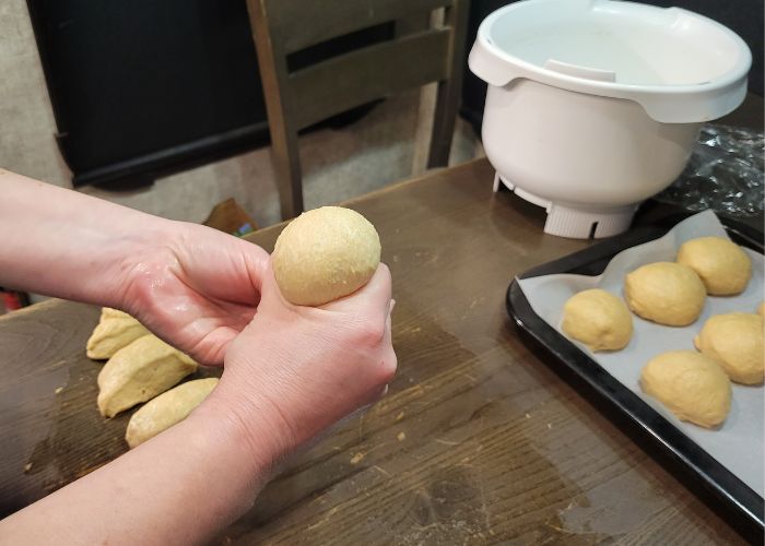 hands shaping whole wheat dinner roll dough balls