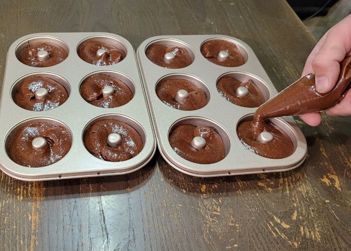 using a piping bag to fill the donut pans. I filled them slightly too high here.