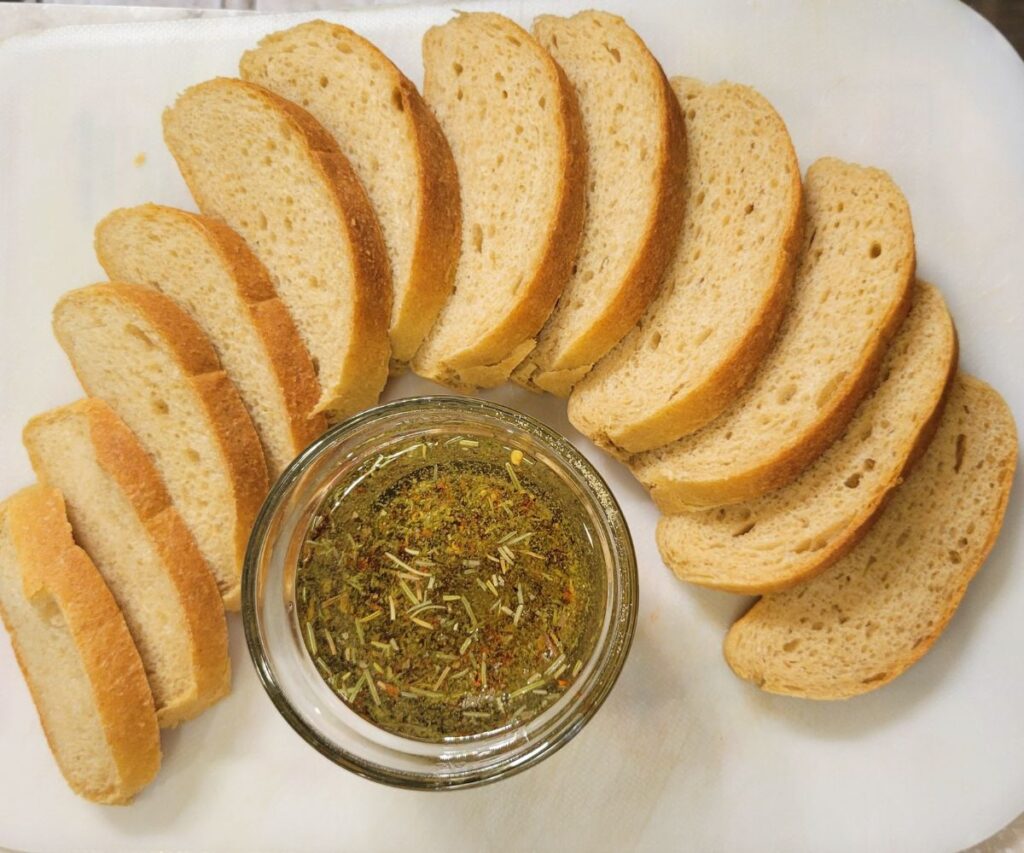 Simple seasoned Dipping olive Oil With sliced Italian bread placed around the glass bowl of oil