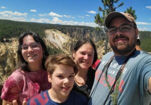 a family of four people outside standing in front of the grand canyon of Yellowstone. about me section