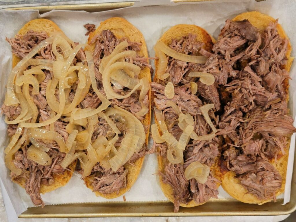 putting carmelized onions on the beef to make french dip subs