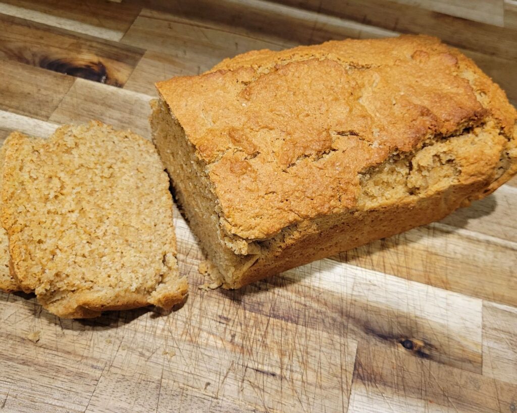 a sliced loaf of home ground flour beer bread on a wooden counter