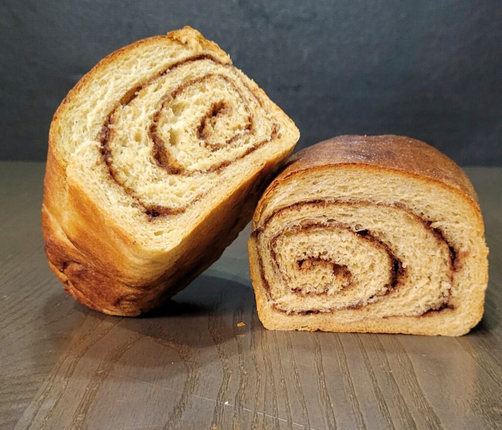 a homemade loaf of Cinnamon Swirl Bread cut in half showing the beautiful swirl.