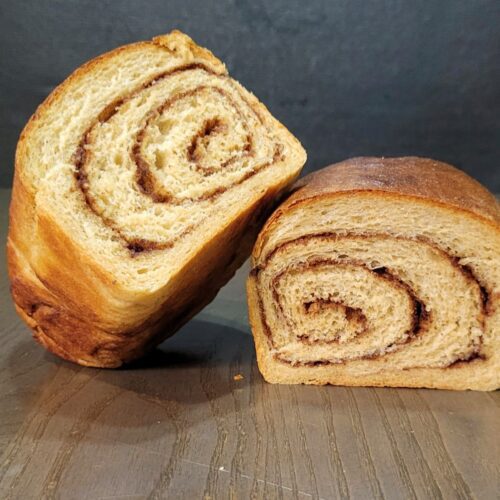 a homemade loaf of Cinnamon Swirl Bread cut in half showing the beautiful swirl.