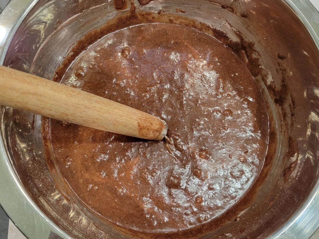 a metal bowl full of chocolate cake batter made with unsifted fresh milled flour