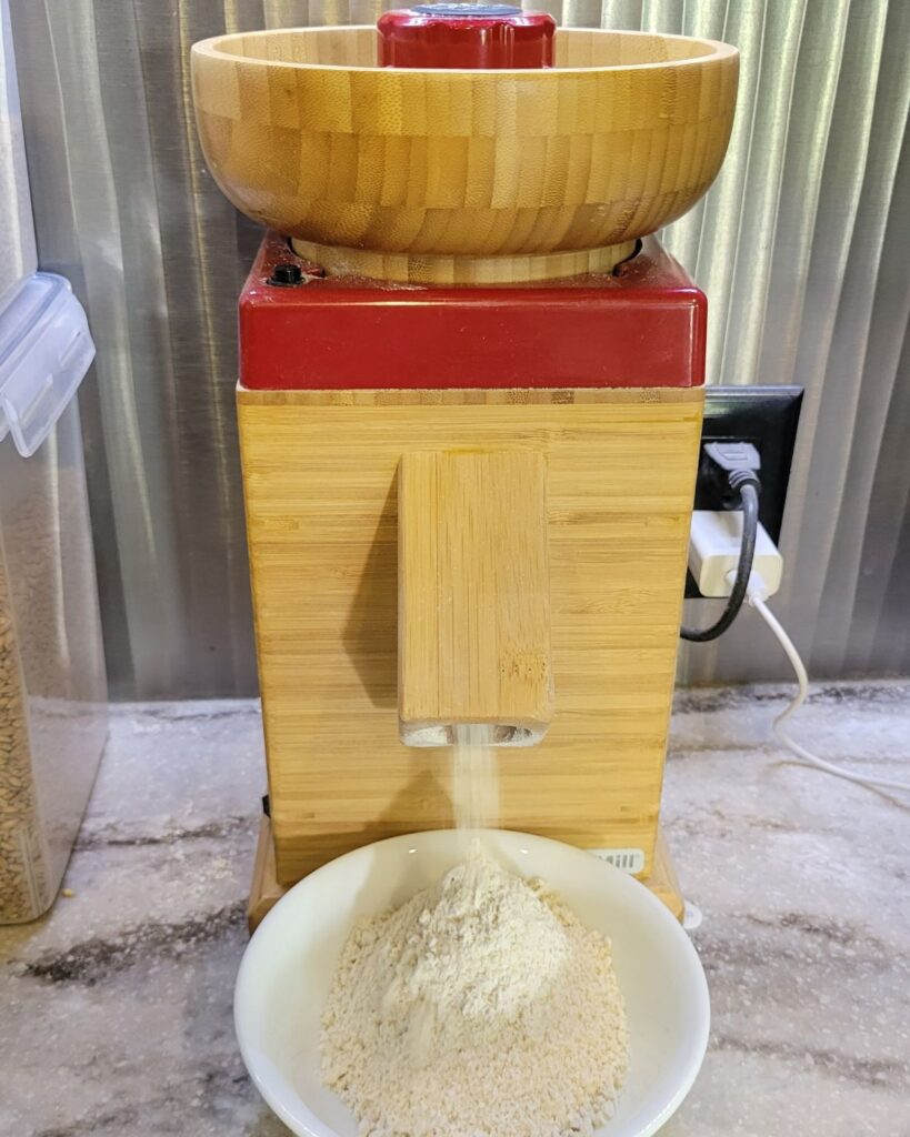 bamboo nutrimill harvest grain mill actively milling wheat to get freshly milled flour.