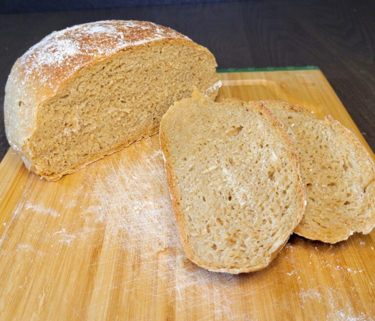 sliced no knead artisan bread loaf made with fresh milled flour sitting on a bamboo cutting board