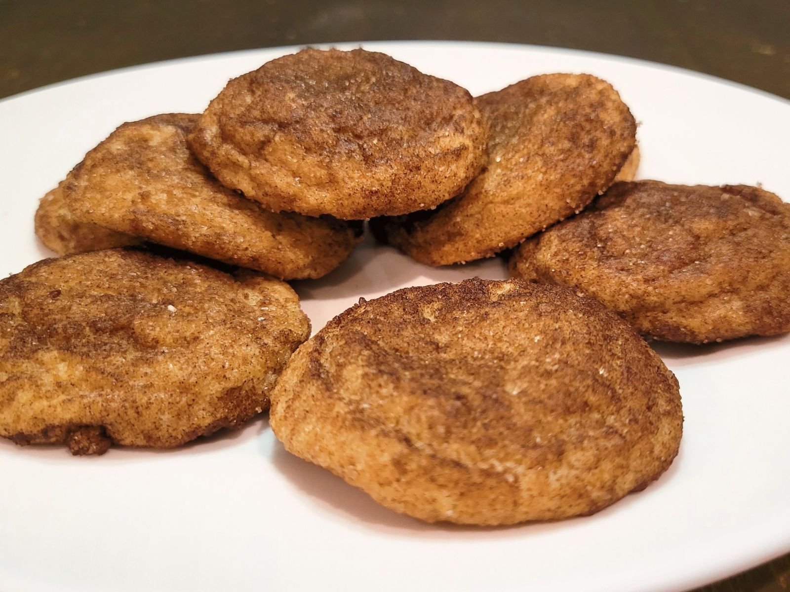 a white plate full of Chewy snickerdoodles fresh milled flour cookies. cinnamon and sugar coating all around the baked cookies.