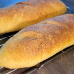 a close up of two french bread baguettes sitting on a wire rack.