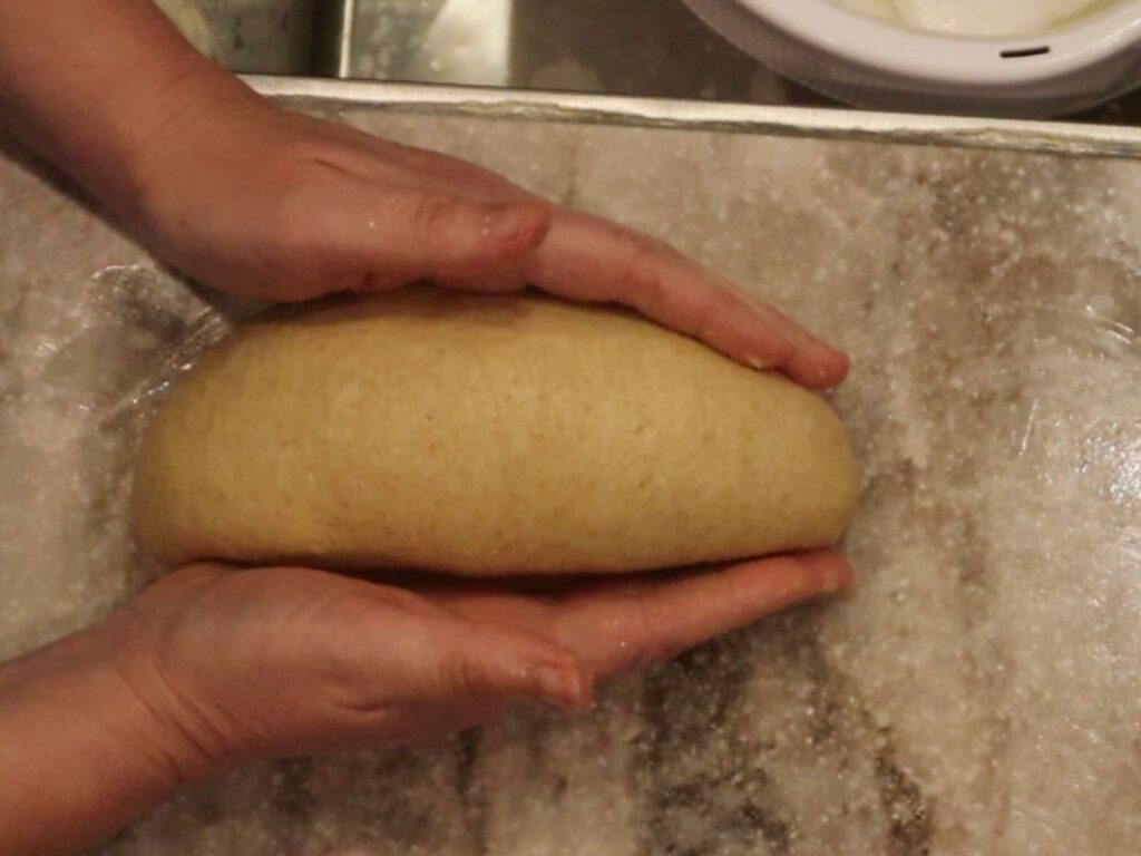 hands shaping bread dough into a loaf