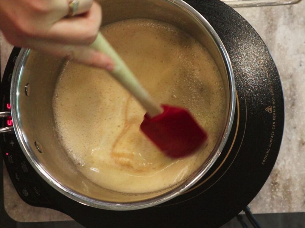 hand using a red spatula to stir browning butter