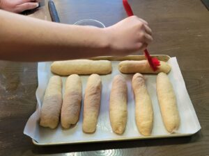 hands brushing the dough with water & baking soda with a pastry brush