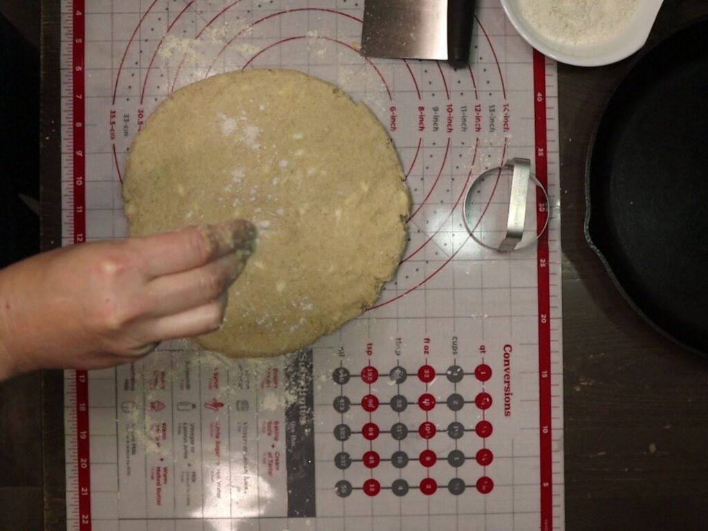 hand flouring biscuits dough disk with fresh milled flour