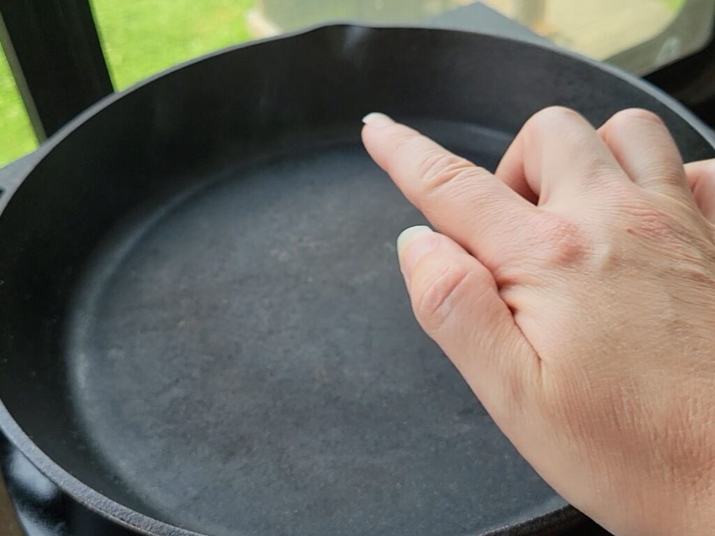 finger pointing at smoke coming from a cast iron pan