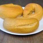three NY Style Bagels Made with fresh milled flour unsliced, baked golden brown on a white plate