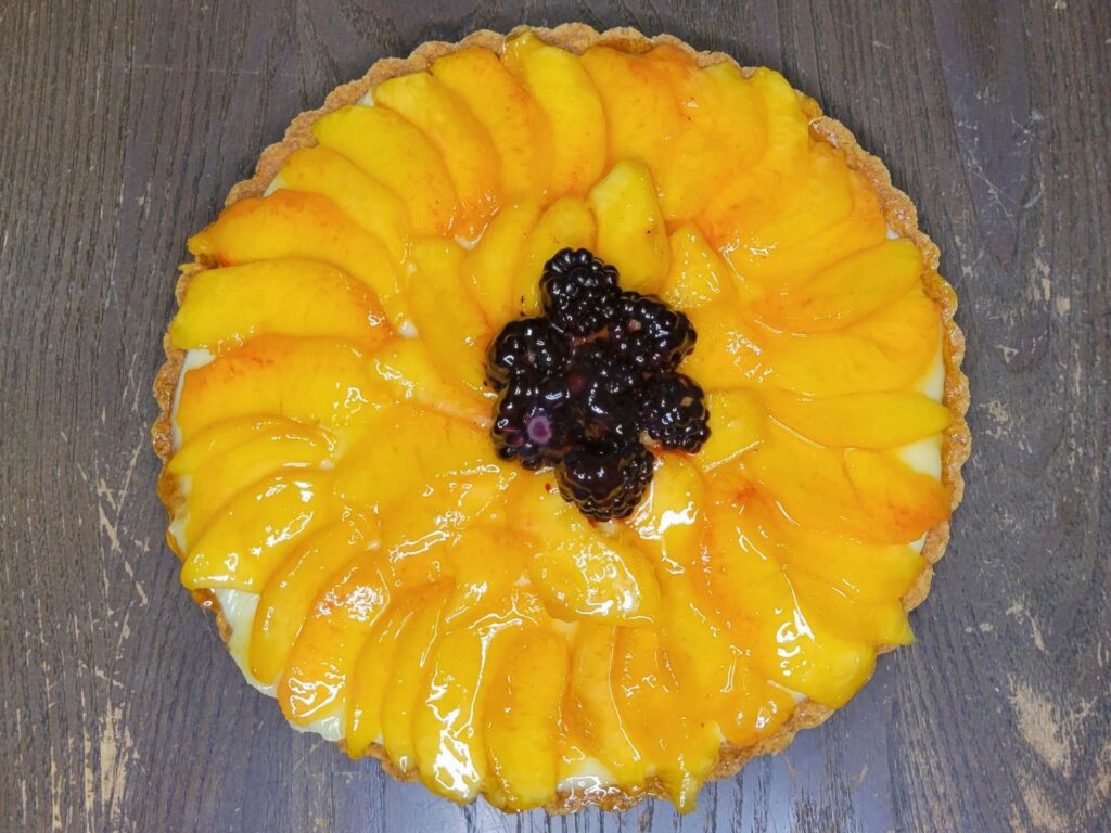 sliced fresh peaches and blackberries on a fruit tart
