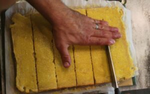 hands using a knife to cut the fresh milled flour lemon bars