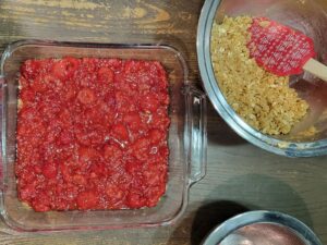 layering the final crisp topping to the raspberry bars made with fresh milled flour and oats