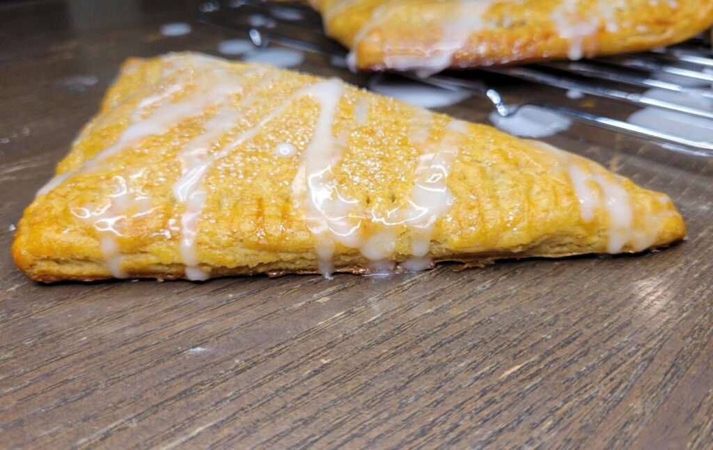 a Apple Turnover Made With Fresh milled flour ruff puff pastry drizzled with homemade icing.