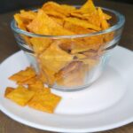 a glass bowl full of Cheddar Cheese Crackers Made with fresh milled flour and a few of the cheez-it type crackers have fallen out of the bowl
