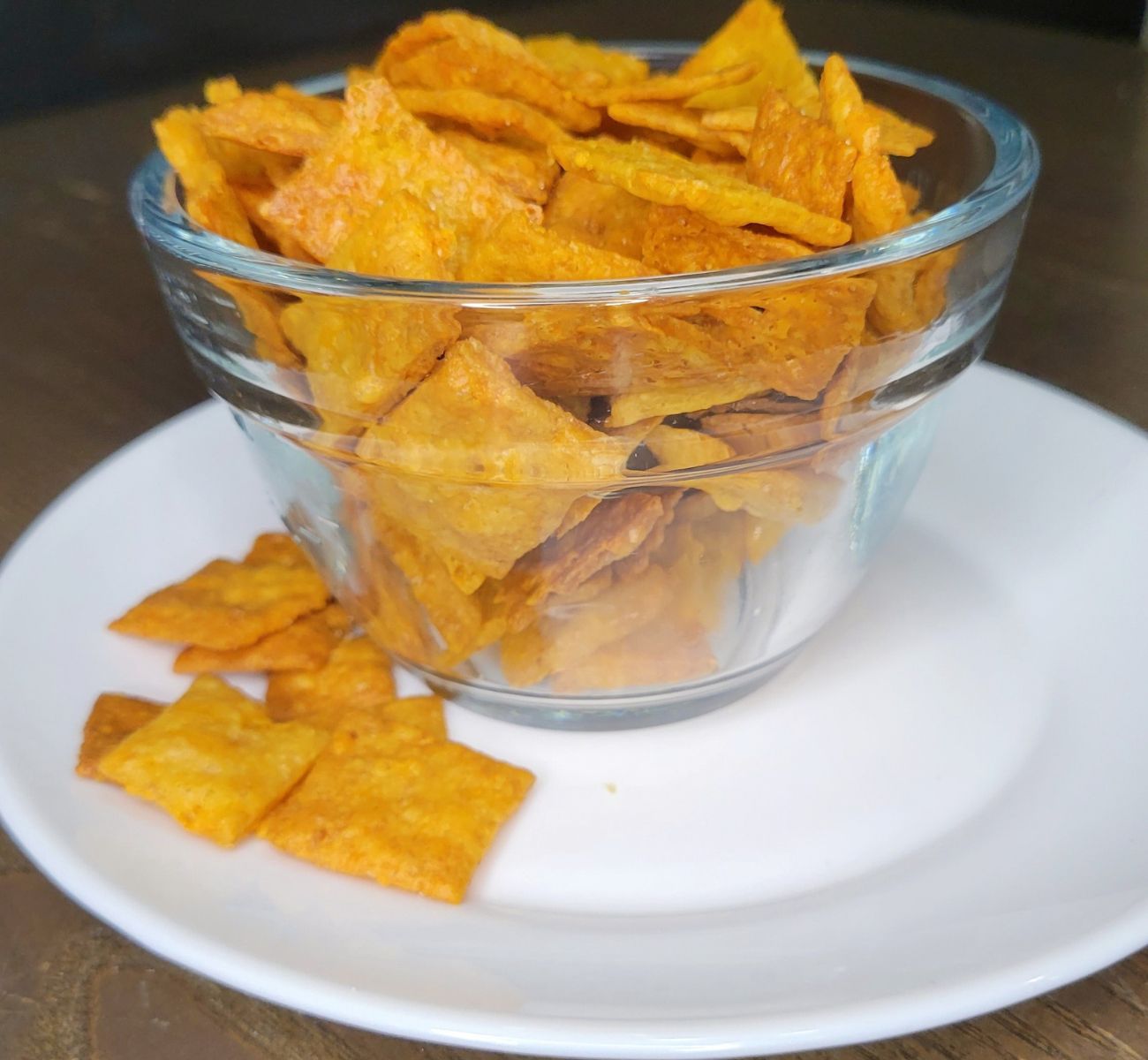 a glass bowl full of Cheddar Cheese Crackers Made with fresh milled flour and a few of the cheez-it type crackers have fallen out of the bowl