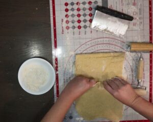 hands folding top of dough down