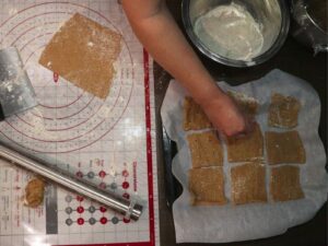 hand using a toothpick and poking holes in the fresh milled flour graham cracker dough squares