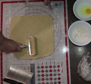 hand rolling dough out into a square