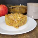 fresh milled flour apple coffee cake in front of a fresh whole red apple and a coffee cup