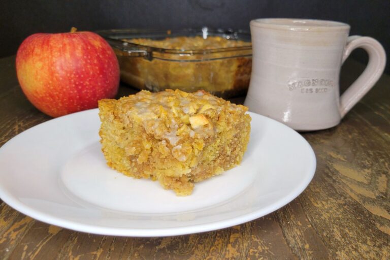 fresh milled flour apple coffee cake in front of a fresh whole red apple and a coffee cup