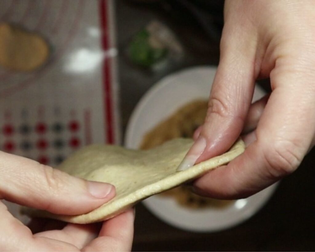 Hands showing the thickness of the rolled out dough