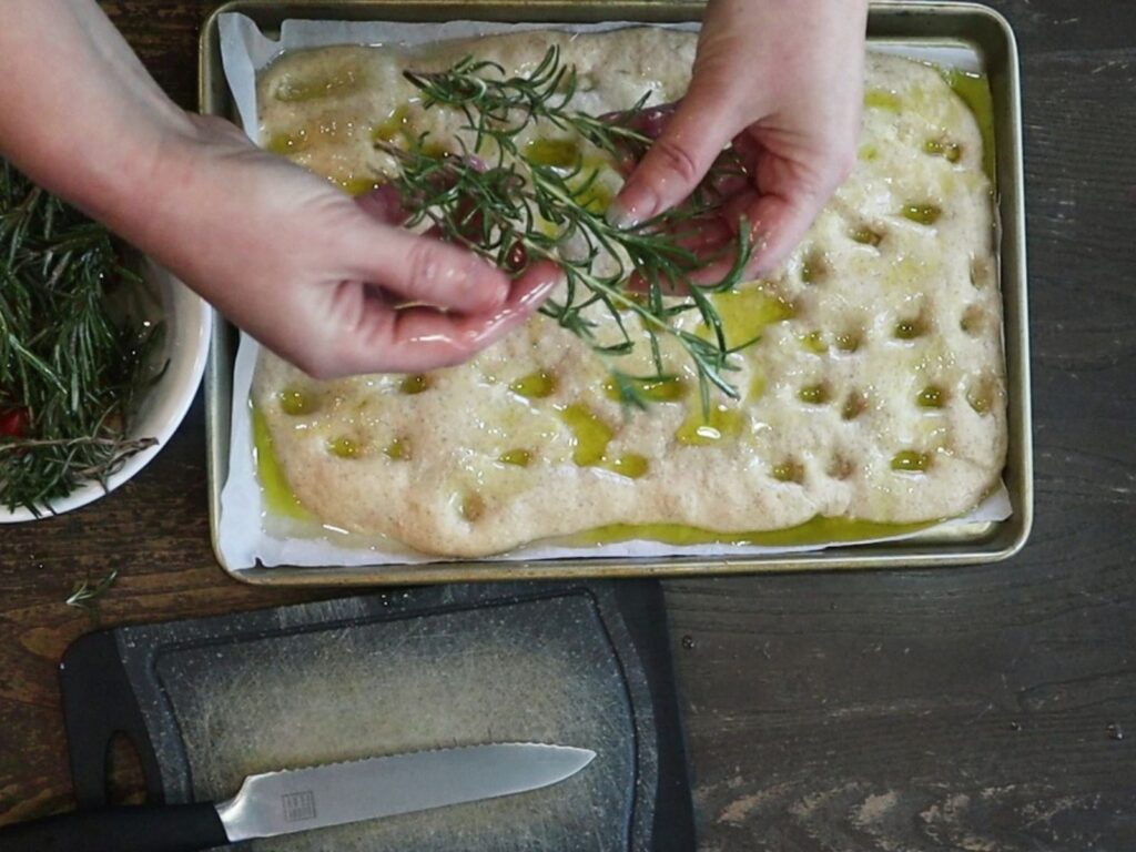 hands coating the toppings with olive oil