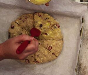 hand using a pastry brush to apply an egg wash on the dough disk.