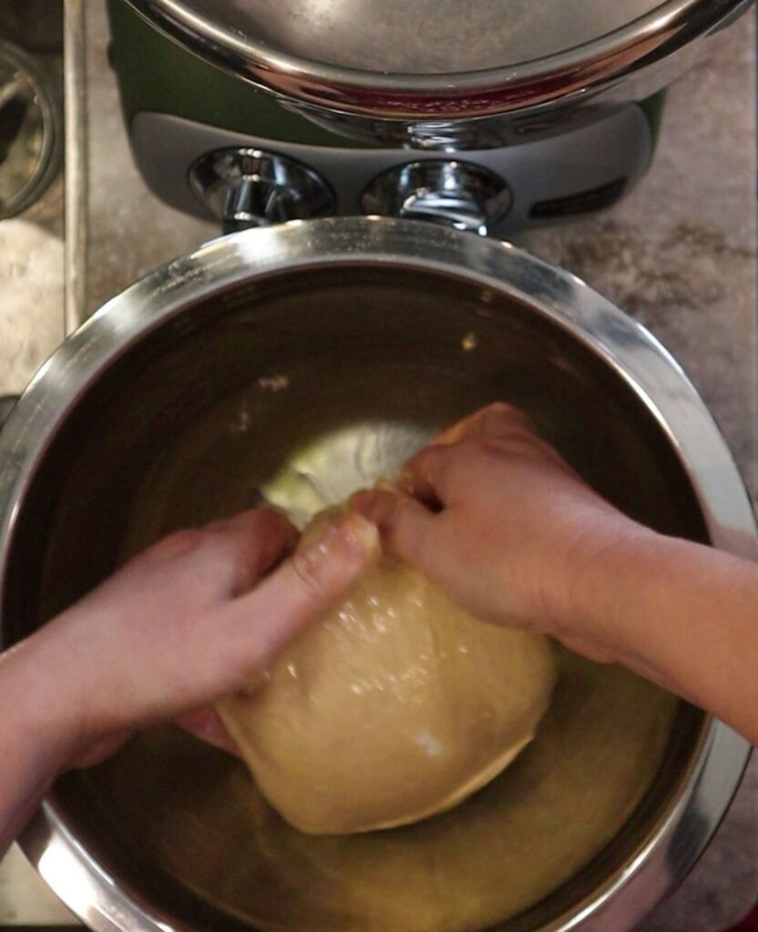 hands oiling the dough and bowl
