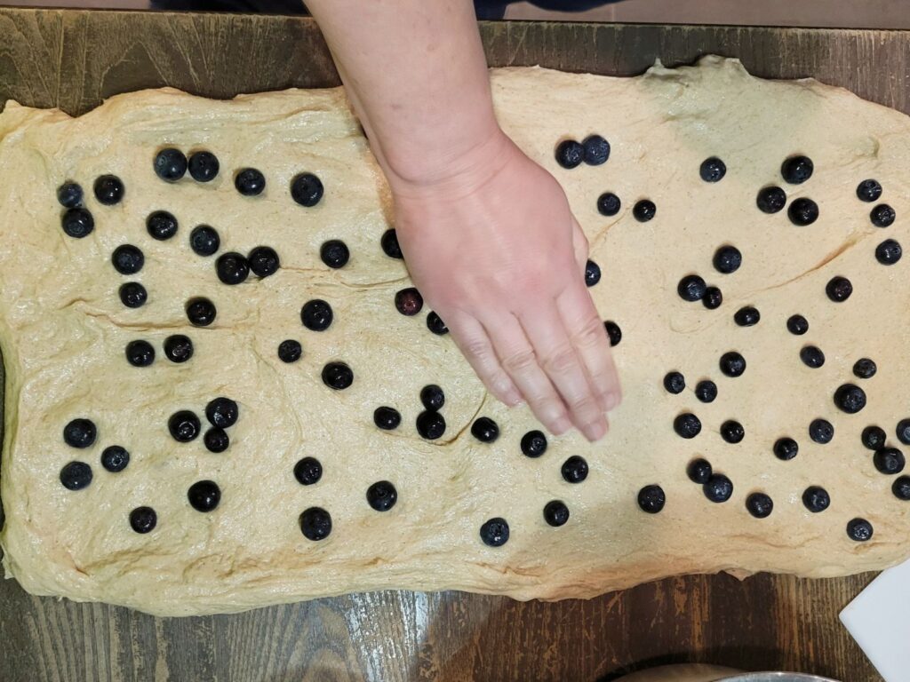 Pressing in the fresh blueberries on the stretched out dough