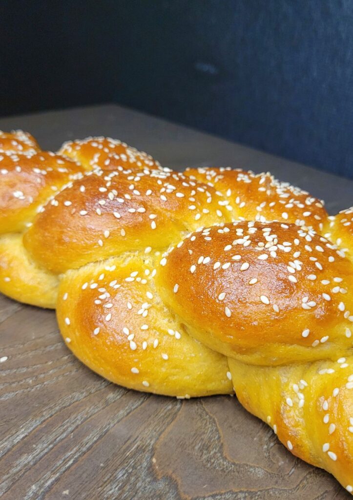 close up of a four strand braided Challah bread loaf with sesame seeds