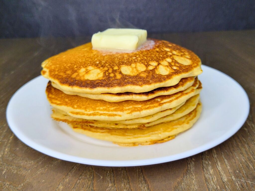 a stack of Fresh Milled Flour Pancakes steaming and topped with melting butter