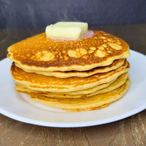 a stack of Fresh Milled Flour Pancakes steaming and topped with melting butter