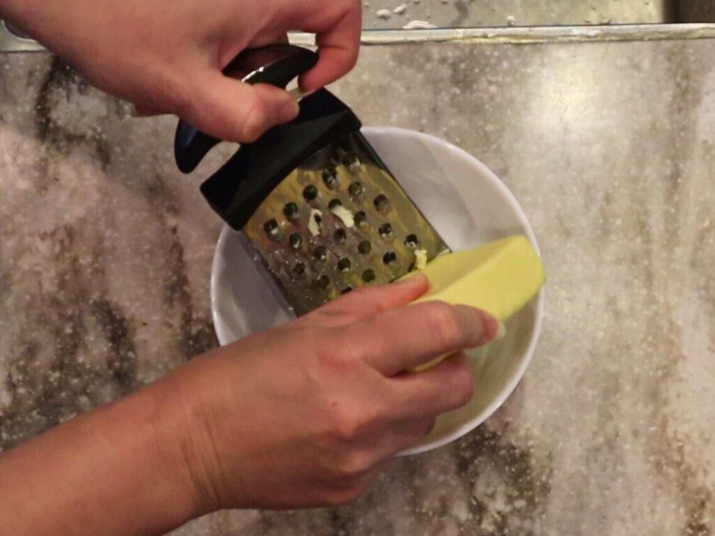 hands grating mozzarella cheese