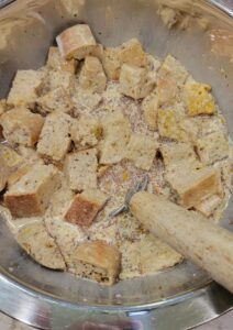adding the wet ingredients to the cubed fresh milled flour bread for the bread pudding