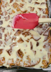 spreading the vanilla glaze over the fresh milled flour bread pudding