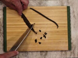 hands slicing open vanilla bean pods