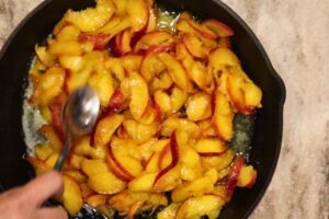 pouring and spreading the peaches over the butter in the skillet