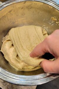 hand doing a stretch and fold the with the dough